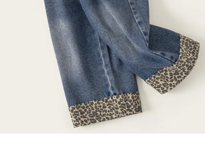 Détail du jean en denim avec revers élégant à motif léopard sur le bas du pantalon