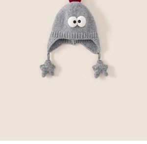 Detail of grey knitted baby hat featuring big eye decor, red pompom, and star charms