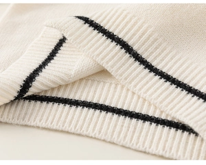 Detailaufnahme des cremefarbenen Strickstoffs mit schwarzen Streifen am Rippbündchen