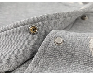 Détail d'une veste baseball grise pour enfant avec bouton pression en métal poli