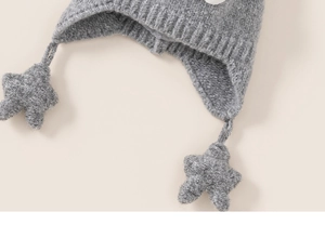 Detailed macro view of gray knitted child winter hat with soft star-shaped pendant detail