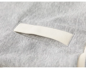Gros plan sur la maille grise et la garniture d'une poche de veste pour enfant
