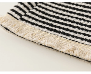 Detail von schwarz-weiß gestreiftem Strickstoff mit goldfarbenen Fransenakzenten