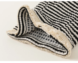 Makro-Detail von gestreiftem Strickstoff mit beigen Fransen und goldenem Metallic-Garn