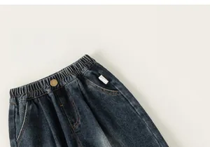 Detail of kids washed denim jeans showing elastic waistband and vintage metal button