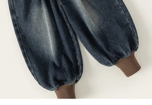 Detail of dark blue denim jeans showing the flexible brown ribbed elastic ankle cuffs