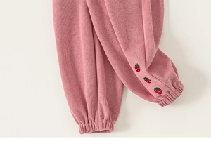 Nahaufnahme einer rosa Kinderhose mit süßer Erdbeerstickerei und elastischen Bündchen