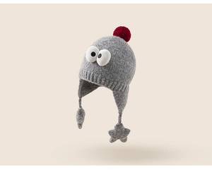 Detail of grey knitted kids earflap hat with big eyes, red pompom and star ties