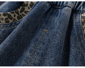 Vue macro du tissu denim bleu avec imprimé léopard et coutures jaunes renforcées