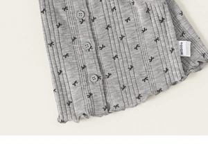 Détail de maille côtelée grise avec motif de nœuds noirs et petits boutons