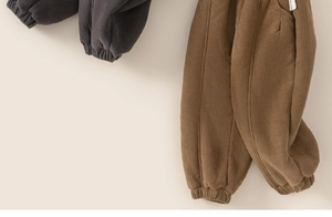 Detail of corduroy texture and elastic ribbed cuffs on winter toddler pants in gray and brown