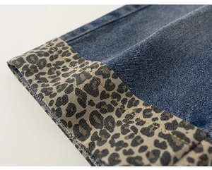 Détail du jean enfant bleu foncé avec revers imprimé léopard tendance et surpiqûres jaunes