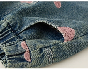 Detail einer elastischen Jeans mit rosa Herzstickerei und seitlichen Taschen