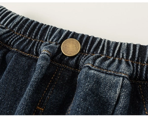 Detail of dark blue denim jeans with elastic waistband and vintage copper button