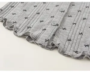 Détail du gilet en maille grise avec imprimé nœuds et ourlet festonné à boutons