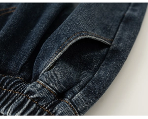 Detail view of boys denim pants with elastic waistband and orange contrast stitching