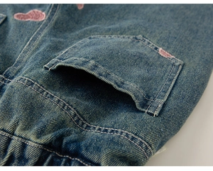 Makro-Detail der blauen Kinderjeans mit rosa Pfoten-Stickerei und elastischem Bund