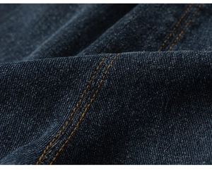 Macro shot of dark blue denim fabric with classic orange double stitching detail