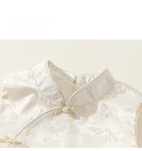 Detailed view of cream jacquard girls' dress featuring floral patterns and pearl bow