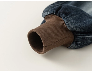 Close-up of boys' denim pants featuring brown ribbed elastic cuffs and washed texture