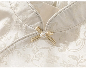 Detail of mandarin collar with jacquard fabric, ribbon bow, and pearl plum blossom ornament