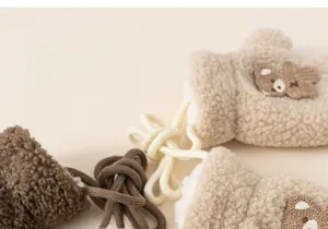 Detail of plush fleece mittens for kids with cute 3D bear embroidery and anti-loss cord