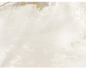Detailed close-up of white floral jacquard fabric with elegant golden trim decoration