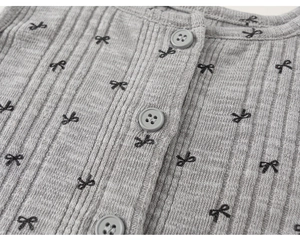 Détail macro du tricot gris côtelé avec broderies nœuds noirs et boutons assortis