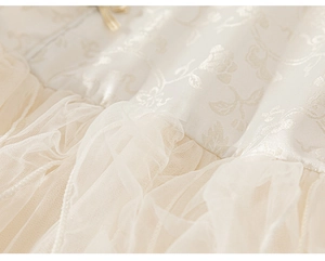 Close-up of cream floral jacquard fabric and layered pleated mesh tulle on the girl dress