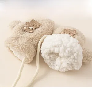Detail of beige fleece baby mittens showing warm faux shearling lining and bear patch