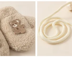 Detail of beige fleece toddlers mittens featuring cartoon bear embroidery and lanyard