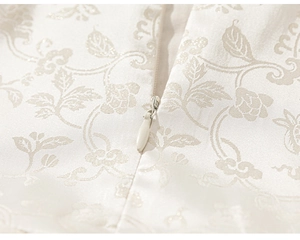 Detailed close-up of an invisible zipper on a cream jacquard floral fabric dress