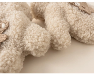 Close-up of soft beige sherpa fleece mittens with a cute brown bear patch detail