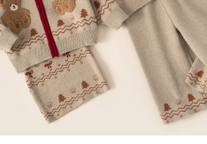 Detail of beige knit set for girls with bear pattern and red zipper closure