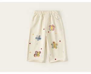 Detalle de los pantalones de algodón crema para niña con bordados florales a cuadros y cintura elástica