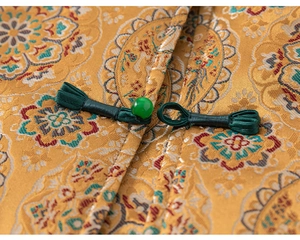 Detail of traditional Chinese brocade fabric with intricate embroidery and green frog button