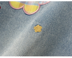 Detalle de mezclilla azul claro con un parche de corazón a cuadros y una pequeña estrella dorada