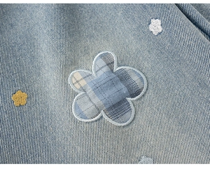 Detalle de mezclilla azul claro con patchwork floral y bordado de estrellas y nubes