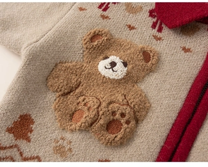 Detail of baby knit cardigan with plush bear patch and autumn maple leaf patterns