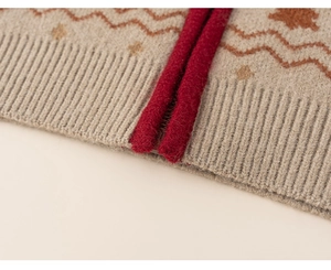 Detail of beige knitted cardigan with reddish wave patterns and thick red border trim