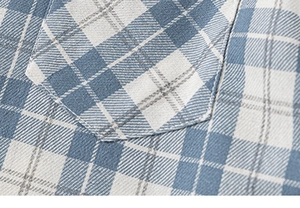 Detailed close-up of blue and white plaid shirt fabric with pocket and neat stitching