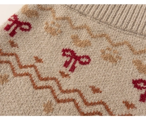 Close-up of beige knit fabric with red bows and paw prints showing ribbed neckline detail