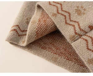 Detailed macro view of khaki knit fabric featuring orange waves and animal paw patterns