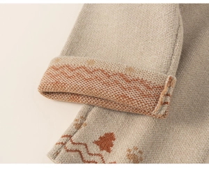 Close-up of knit texture with orange wave patterns and small tree embroidery on beige fabric