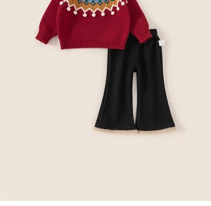 Détail d'un pull festif rouge avec col jacquard et pantalon noir à bordure en fourrure