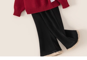 Détail du pull en maille rouge avec pantalon côtelé noir et bordures en fausse fourrure