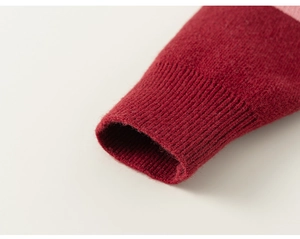 Detailed macro view of the ribbed cuff on a wine red knit cardigan with pink patchwork