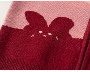 Detailed view of pink and dark red knit cardigan with a cute bunny cartoon embroidery