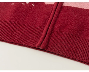 Detail of burgundy knit cardigan showing high-density texture and ribbed hem craftsmanship