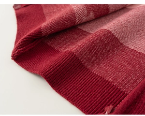 Close-up of red knit cardigan ribbed hem and precision stitching with zipper detail